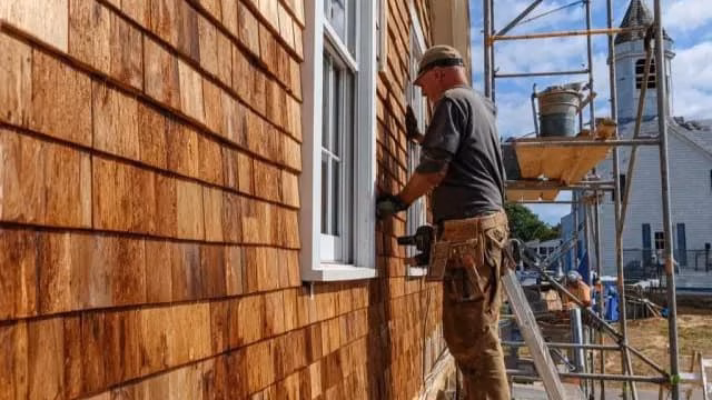 Professional cedar siding installation on a residential exterior, showing properly aligned wood siding panels and detailed finishing