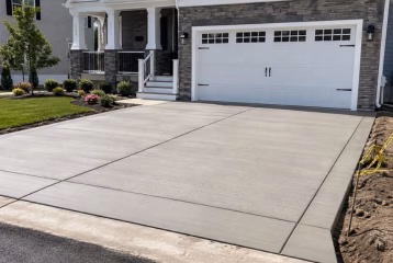 Residential concrete driveway with a clean finished surface leading to a home garage and landscaped front yard.
