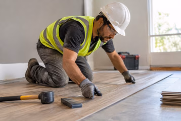 Professional contractor installing wood-look flooring in a residential room.