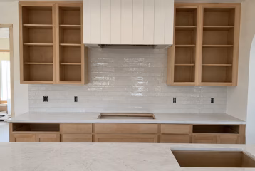 Kitchen backsplash tile installation with unfinished custom cabinetry and countertops